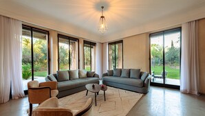 A spacious living room with a large sectional sofa, a coffee table, and a chandelier. - Villa de luxe Sahara  (Marrakech)