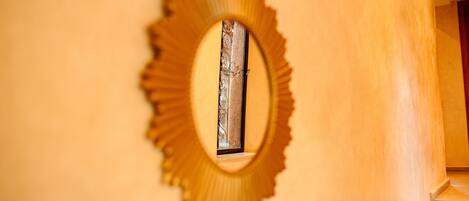 Un miroir rond, orné d’un cadre décoratif, est accroché au mur.