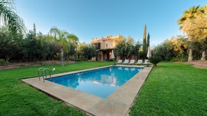 A rectangular swimming pool with a concrete deck, surrounded by a well-maintained lawn and various trees. - Villa de luxe Sahara  (Marrakech)
