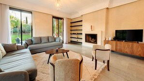 A modern living room with a sofa, chairs, a coffee table, a fireplace, and a TV. - Villa de luxe Sahara  (Marrakech)