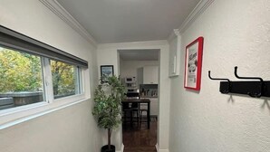 A narrow hallway with a ceiling light, a potted plant, a wooden bench, a black wall-mounted rack, and a framed picture. - The LIFTS: Downtown SLC/ Delta Center/ Pets OK! (Salt Lake City)