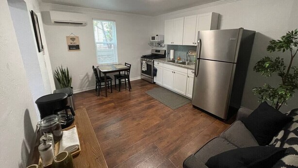 A compact kitchen with a refrigerator, stove, and dining area. - The LIFTS: Downtown SLC/ Delta Center/ Pets OK! (Salt Lake City)