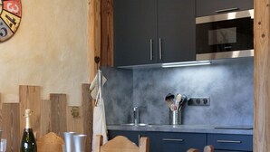 Una cocina moderna con armarios oscuros, un horno de acero inoxidable y una mesa de comedor de madera dispuesta con platos y vasos.