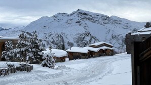 Una montaña nevada con cabañas de madera y un sendero cubierto de nieve.
