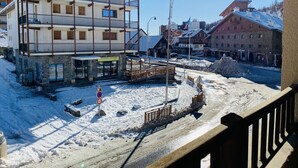 Ein mehrstöckiges Hotel mit Balkonen, einem mit Schnee bedeckten Untergrund und blauem Himmel.