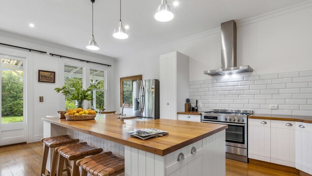 A modern kitchen with a central island, stainless steel appliances, and wooden bar stools. - Botham's Beauty - Blenheim Holiday Home (Blenheim)