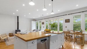A modern kitchen with a wooden island, white cabinetry, and a built-in dishwasher. - Botham's Beauty - Blenheim Holiday Home (Blenheim)