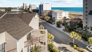 A coastal hotel with multiple floors, a street view, and a beach in the background. - Steps Away From The Ocean (North Myrtle Beach)