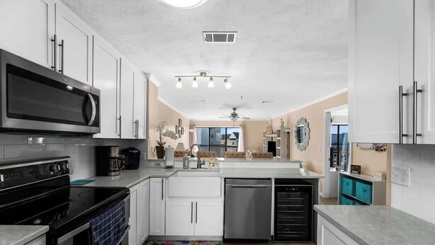 A modern kitchen with white cabinets, stainless steel appliances, and a central island. - Steps Away From The Ocean (North Myrtle Beach)