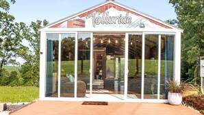 A modern, glass-fronted building named 'Telluride' with a wooden deck and a landscaped garden. - Tiny Houses of French Village Tranquil & Relaxing (French Village)