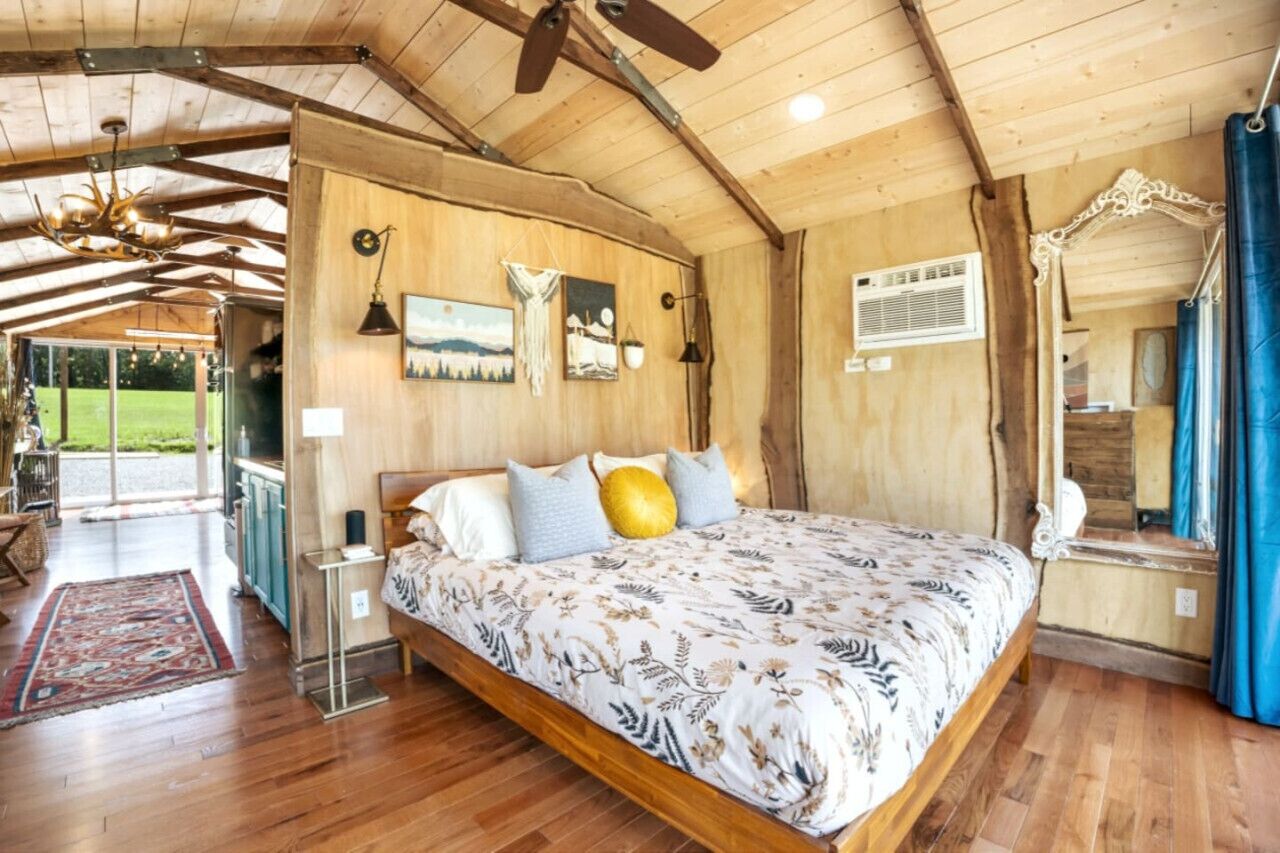 Un dormitorio espacioso con una cama grande, vigas de madera en el techo y vistas al exterior.