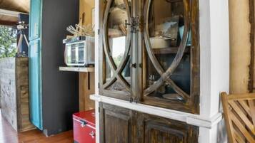 Un meuble en bois avec des portes en verre et une valise rouge posée sur un plancher en bois.