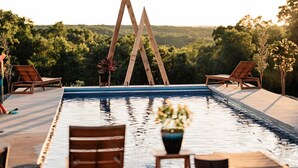 Ein Poolbereich mit Holzliegen und freiem Blick auf den umliegenden Wald.