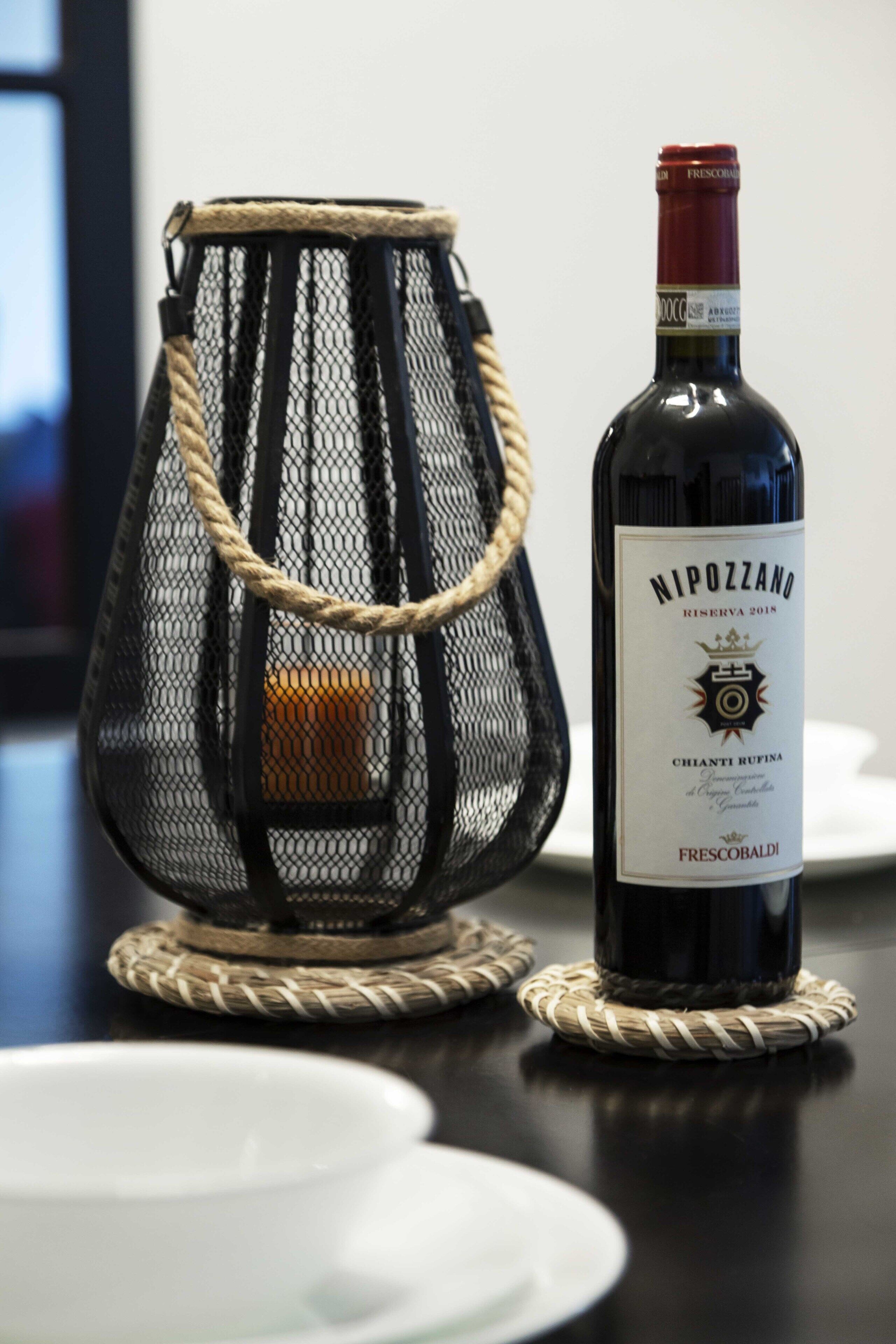 Una botella de vino Nipozzano junto a una cesta tejida sobre una mesa.