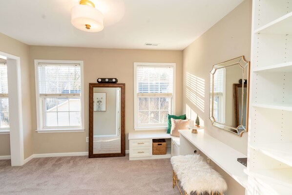 Relax in a serene space with a large mirror, vanity, and plush bench.