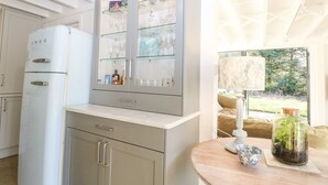 A kitchen with a built-in cabinet, a white refrigerator, and a round table with a decorative bowl and a glass jar. - Meon Boscage (Southampton)