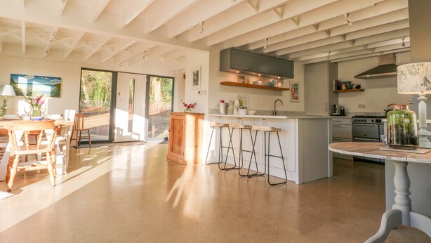 A spacious kitchen with a large island, bar stools, and a dining area with a table and chairs. - Meon Boscage (Southampton)