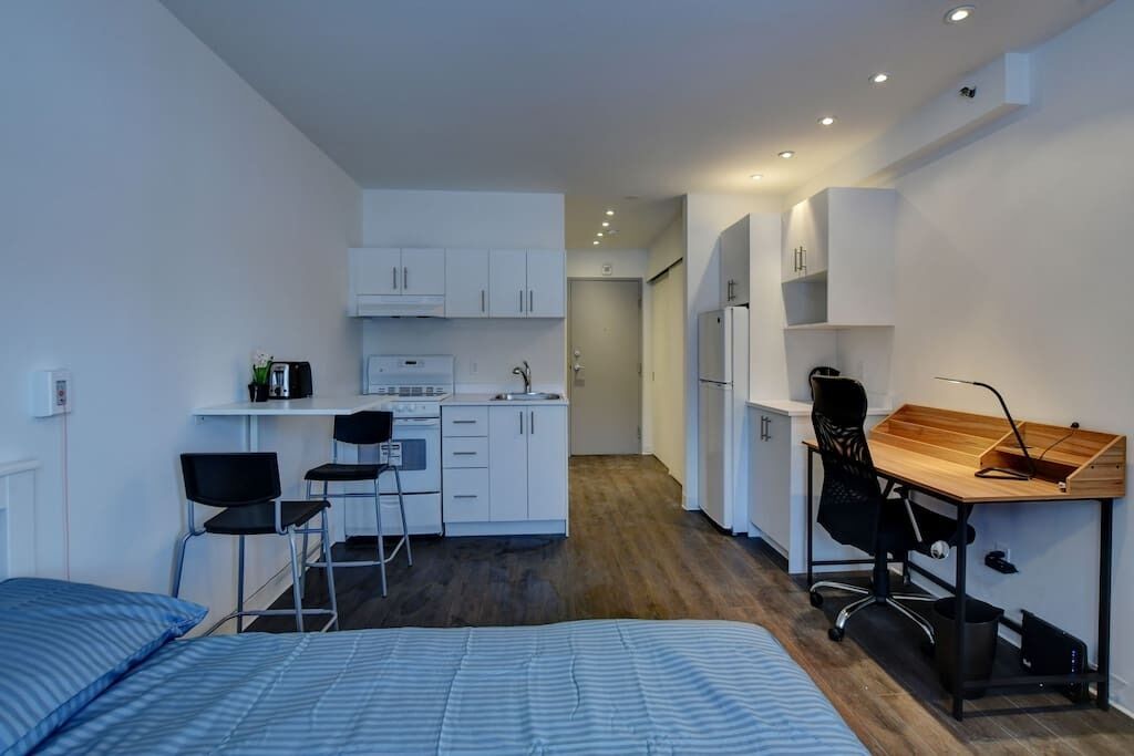 Une petite pièce comprenant un coin cuisine, un lit, un bureau et une chaise.