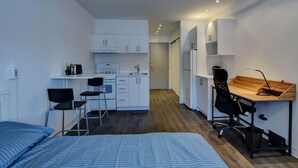 A compact room with a kitchenette, a bed, a desk, and a chair. - Spacious studio Laval, all included, wifi, parking (Laval)