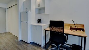 Eine kleine Küchenzeile mit Kühlschrank, Kaffeemaschine und einem Tisch mit Stuhl.