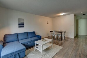 A living room with a blue sofa, a white coffee table, and a dining area with a table and chairs.