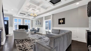 A modern living room with a grey sectional sofa, a white armchair, a patterned rug, and a chandelier. - Lux Home in Chicago 7mins Downtown (Chicago)