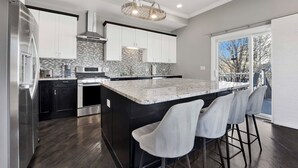 A modern kitchen with a large island, stainless steel appliances, and a view to the outside. - Lux Home in Chicago 7mins Downtown (Chicago)