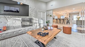 A modern living room with a stone accent wall, a wooden coffee table, and a large window. - Plant City: Pool, Hot Tub & Guest House (Plant City)