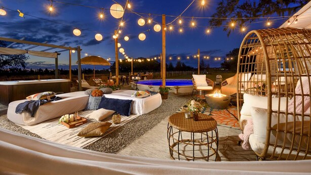 An outdoor lounge area with string lights, a hot tub, and a cozy seating arrangement. - Plant City: Pool, Hot Tub & Guest House (Plant City)