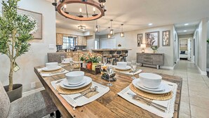 A dining area with a wooden table set for four, surrounded by chairs, a chandelier, and a potted plant. - Plant City: Pool, Hot Tub & Guest House (Plant City)