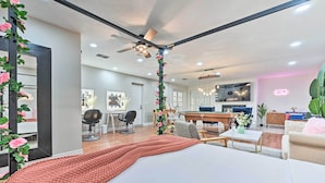 A modern bedroom with a large bed, a ceiling fan, and a view into the living area. - Plant City: Pool, Hot Tub & Guest House (Plant City)