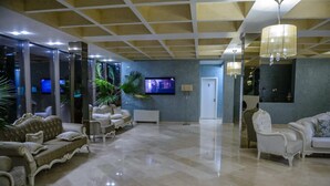 A spacious lobby with a polished marble floor, elegant furniture, and a television mounted on the wall. - Turquoise Hotel (Venus)