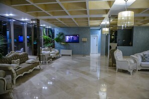 A spacious lobby with a polished marble floor, elegant furniture, and a television mounted on the wall. - Turquoise Hotel (Venus)