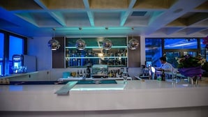 Zona de bar moderna con un cantinero, mostrador y estantes llenos de botellas.