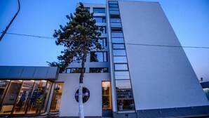 A modern building with a large glass facade, a tree in front, and a visible sign that reads "JOTU08". - Turquoise Hotel (Venus)