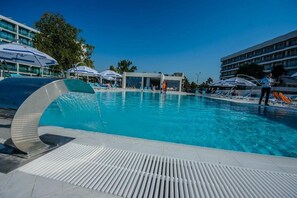 A swimming pool with lounge chairs and umbrellas, surrounded by modern buildings. - Turquoise Hotel (Venus)