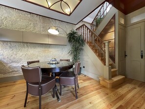 Un coin repas avec une table ronde, quatre chaises, une plante en pot et un escalier avec des rampes en bois.