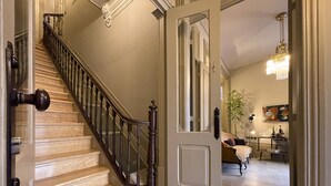 A staircase with wooden steps and a dark handrail leading to a room with a door.