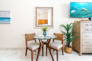 Un coin repas avec une table en verre, des chaises en osier et un buffet en bois.