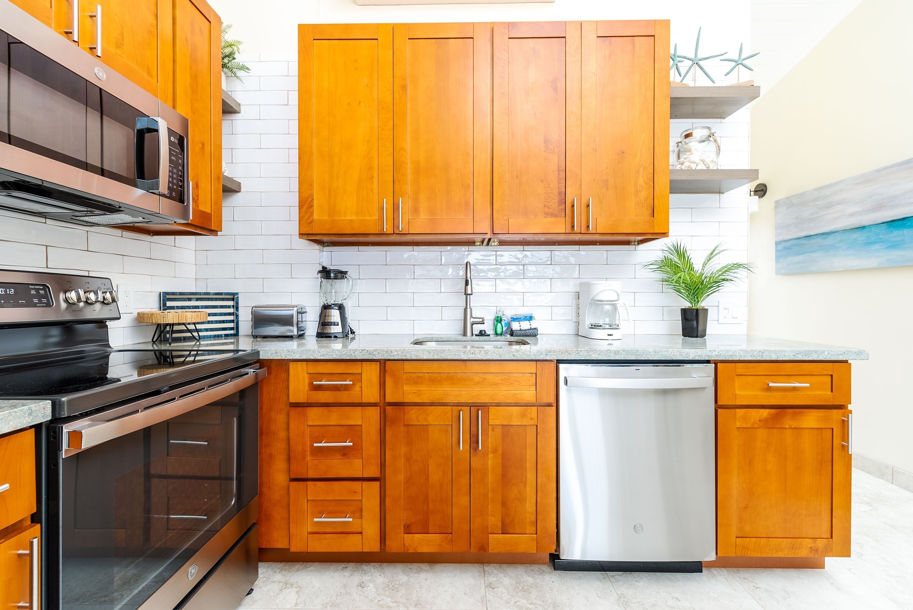 A kitchen with wooden cabinets, a stainless steel dishwasher, and a microwave.