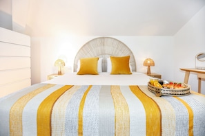Ein modernes Schlafzimmer mit einem großen Bett, zwei Nachttischlampen, einem runden Spiegel und einem Frühstücksbrettchen auf dem Bett.