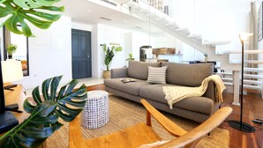 A modern living room with a sofa, coffee table, and a staircase. - Zen and Tan Apartment (Faro)