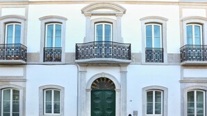 A building with a green door, multiple windows, and balconies with wrought iron railings. - Zen and Tan Apartment (Faro)