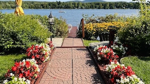 A paved pathway leading to a lake with a boat in the distance. - Cottage Tranquility family waterfront mountains (Dunham)