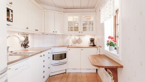 Una cocina con armarios blancos, encimera de madera, estufa y ventana con flores.