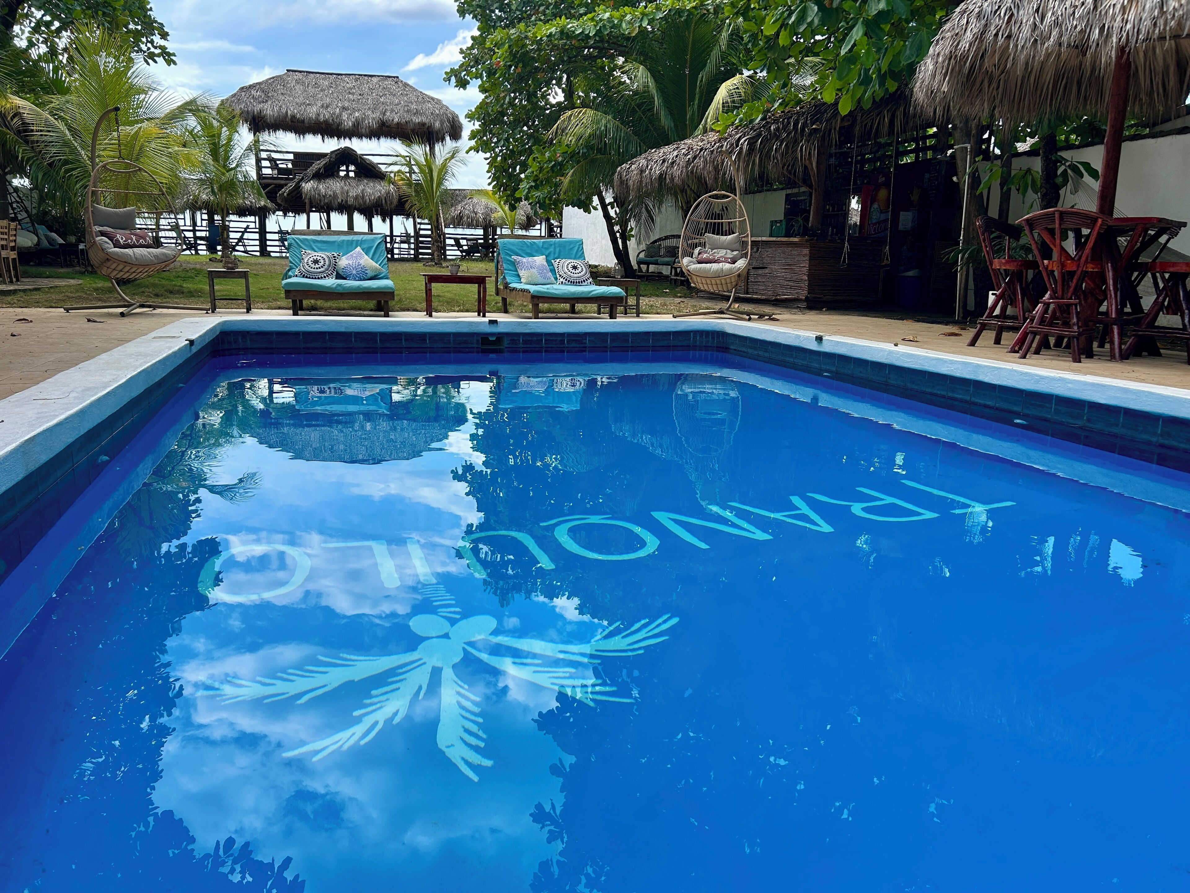 A swimming pool with a tropical setting, including lounge chairs and thatched-roof structures.