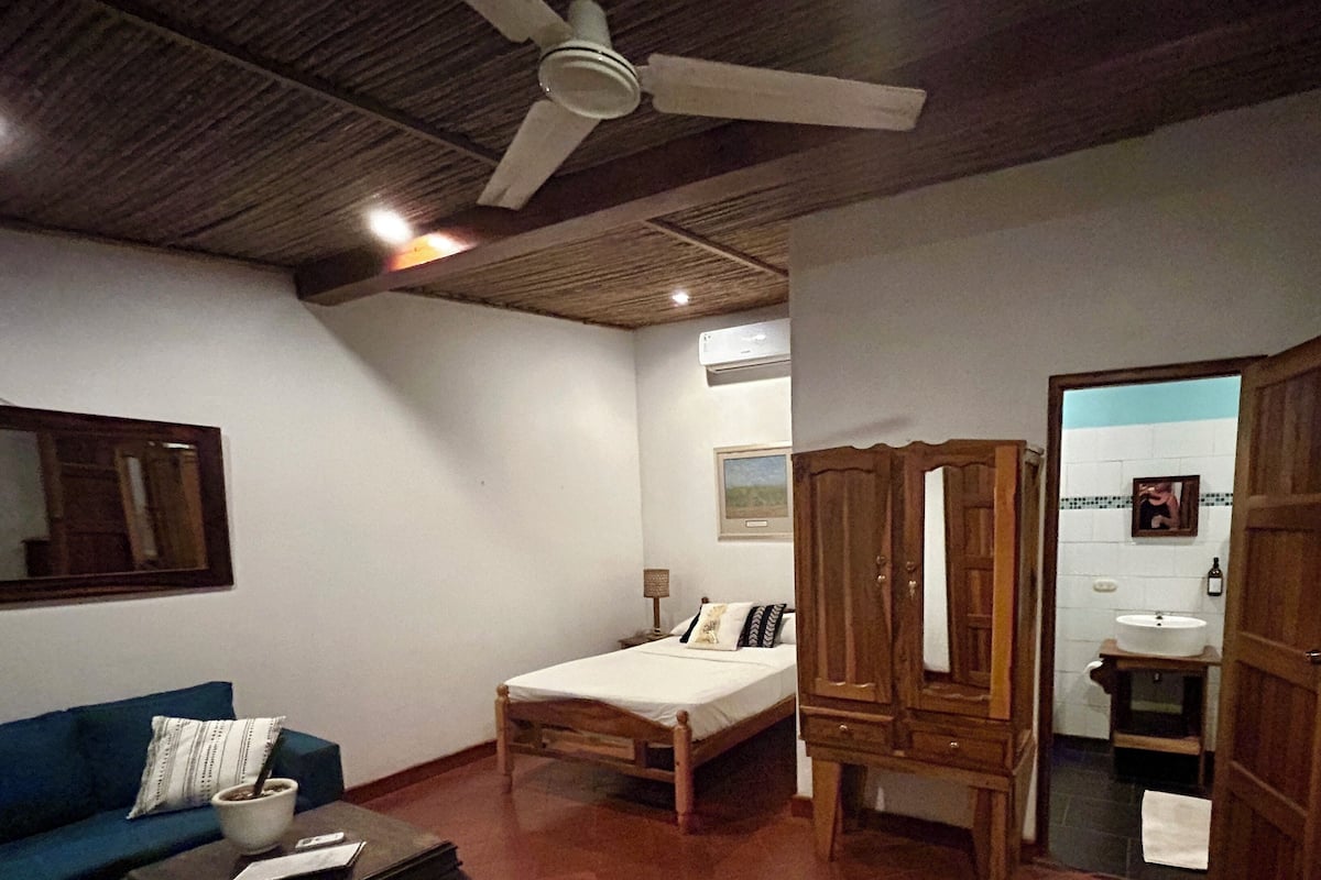 Una habitación con cama, armario de madera, sofá azul y mesa de centro.