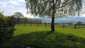 A fenced grassy field with a tree in the foreground and a distant view of a landscape. - Le Cottage, Country house 15 minutes from the beaches of Deauville (Saint-Julien-sur-Calonne)