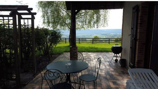 An outdoor patio with a table and chairs, a pergola, and a view of a green landscape. - Le Cottage, Country house 15 minutes from the beaches of Deauville (Saint-Julien-sur-Calonne)