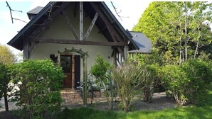 A traditional half-timbered house with a stone entrance, surrounded by lush greenery and trees. - Le Cottage, Country house 15 minutes from the beaches of Deauville (Saint-Julien-sur-Calonne)